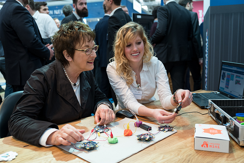 Die Bundesministerin lässt sich den Calliope Mini zeigen, eine Mikrocontroller-Platine, mit der bereits Drittklässlerinnen und -klässler das Programmieren erproben können.; Quelle: BMWi/Maurice Weiss