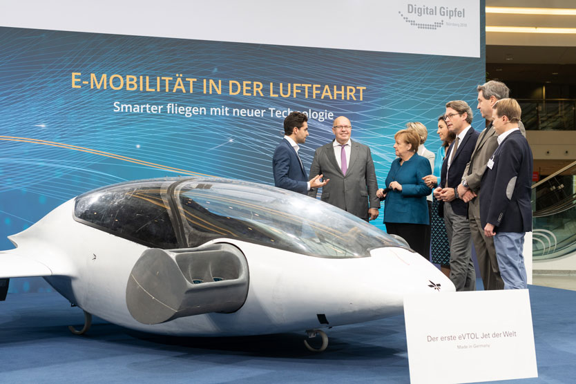 Gemeinsam mit Kanzlerin Merkel lässt sich Bundesminister Altmaier den ersten eVTOL-Jet der Welt präsentieren, einen elektrisch angetriebenen, autonom fliegenden Senkrechtstarter für den Personentransport.